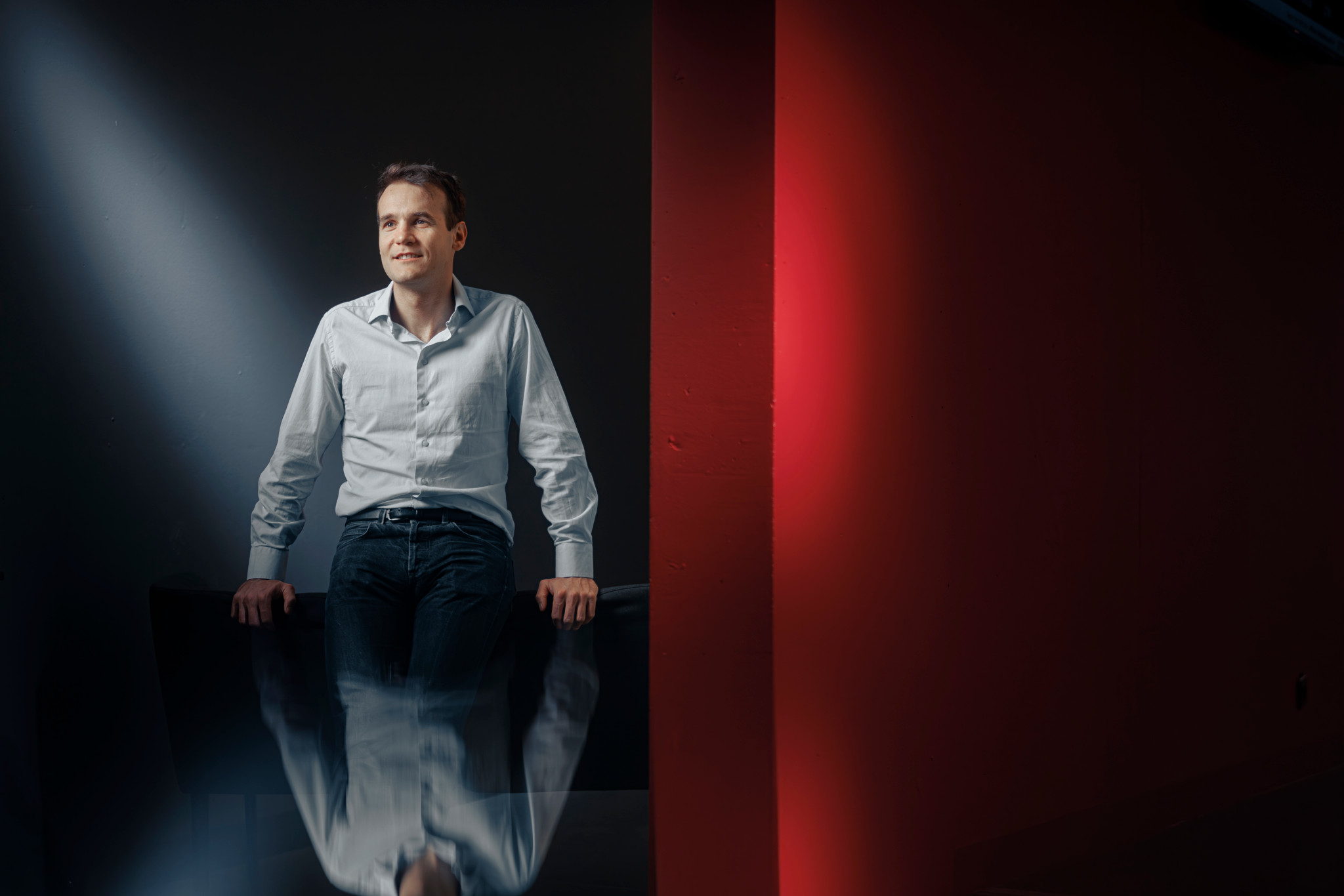 Pierre Baqué, CEO de Neural Concept, assis dans un bureau moderne avec un éclairage contrastant à EPFL Lausanne.