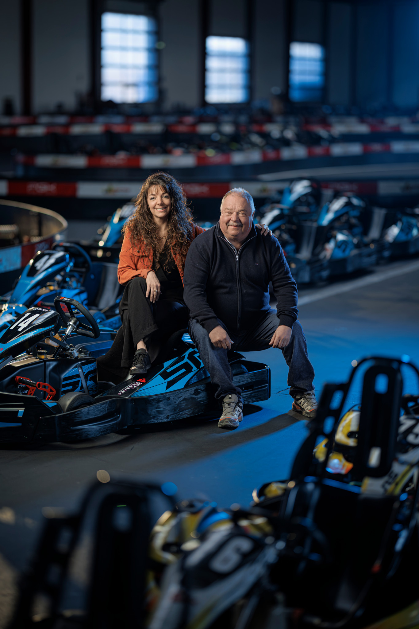 Patrice Lorimier et sa fille Stéphanie, propriétaires du Karting de Payernland, posent assis sur des karts dans leur piste intérieure à Payerne.