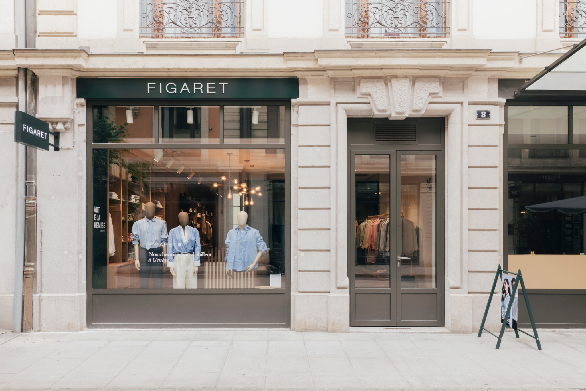 Façade d’une boutique Figaret avec mannequins portant des chemises et une rangée de vêtements à l’intérieur.