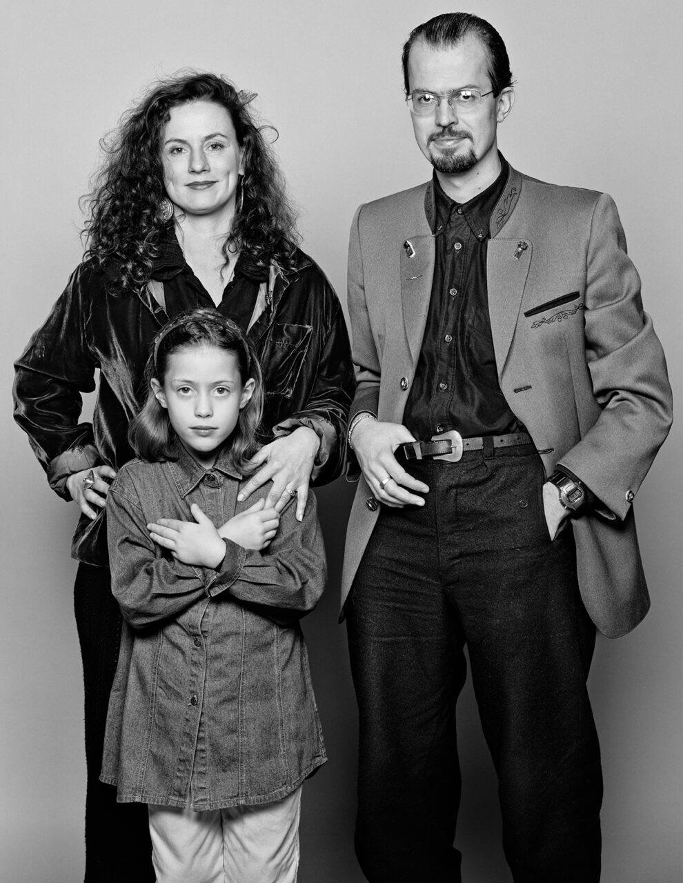 Portrait en noir et blanc d’une famille de trois personnes: une femme aux cheveux bouclés, un homme en veste et une enfant aux bras croisés.