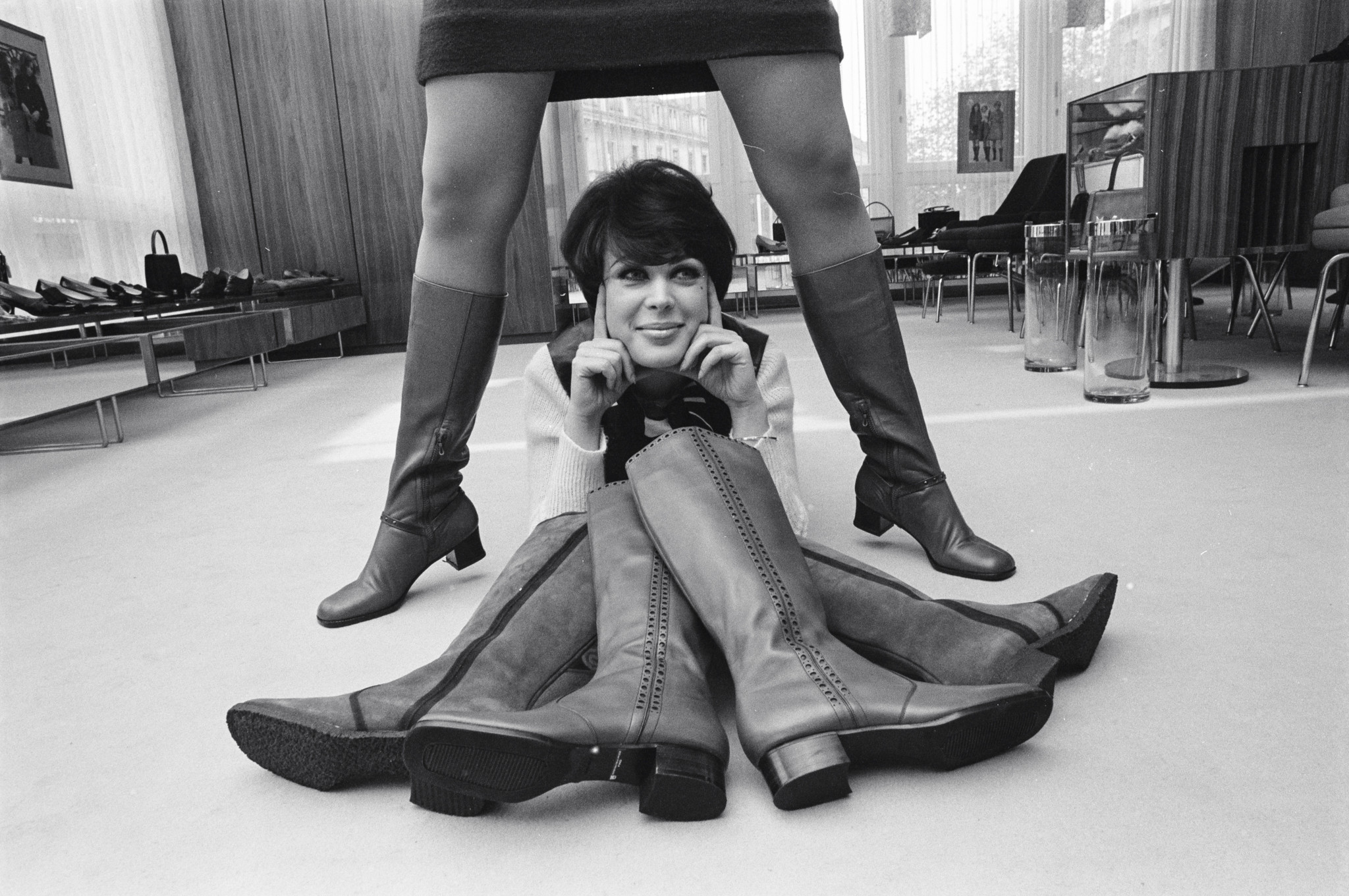 Intérieur élégant en bois d’une boutique de chaussures vintage avec des clients assis discutant, entourés de présentoirs et d’un éclairage chaleureux.
