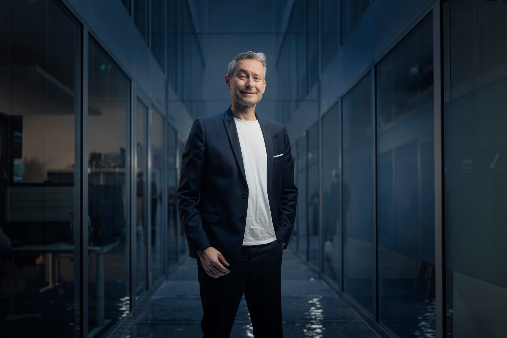 Jan De Schepper, CEO de Yuh, souriant dans un couloir aux parois vitrées des bureaux de l’entreprise à Gland.
